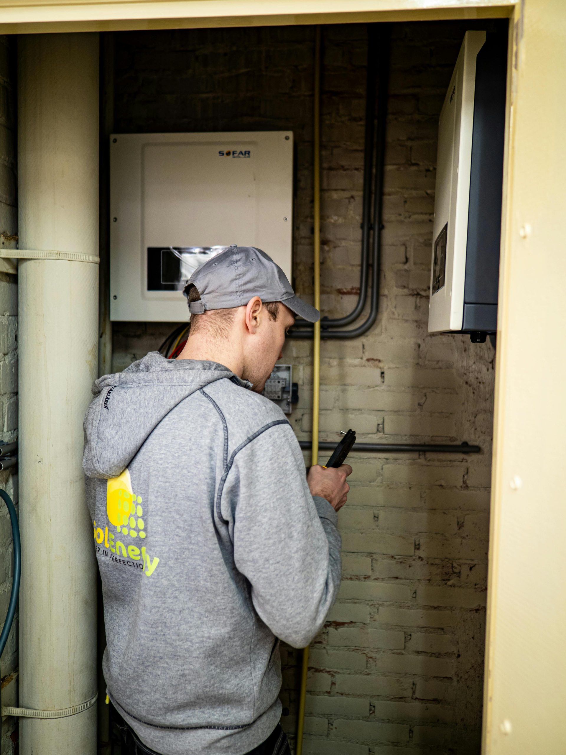 pexels-sdvmovies-29206492 Solar panel maintenance and storage battery inspections Farnborough Man inspecting storage batteries