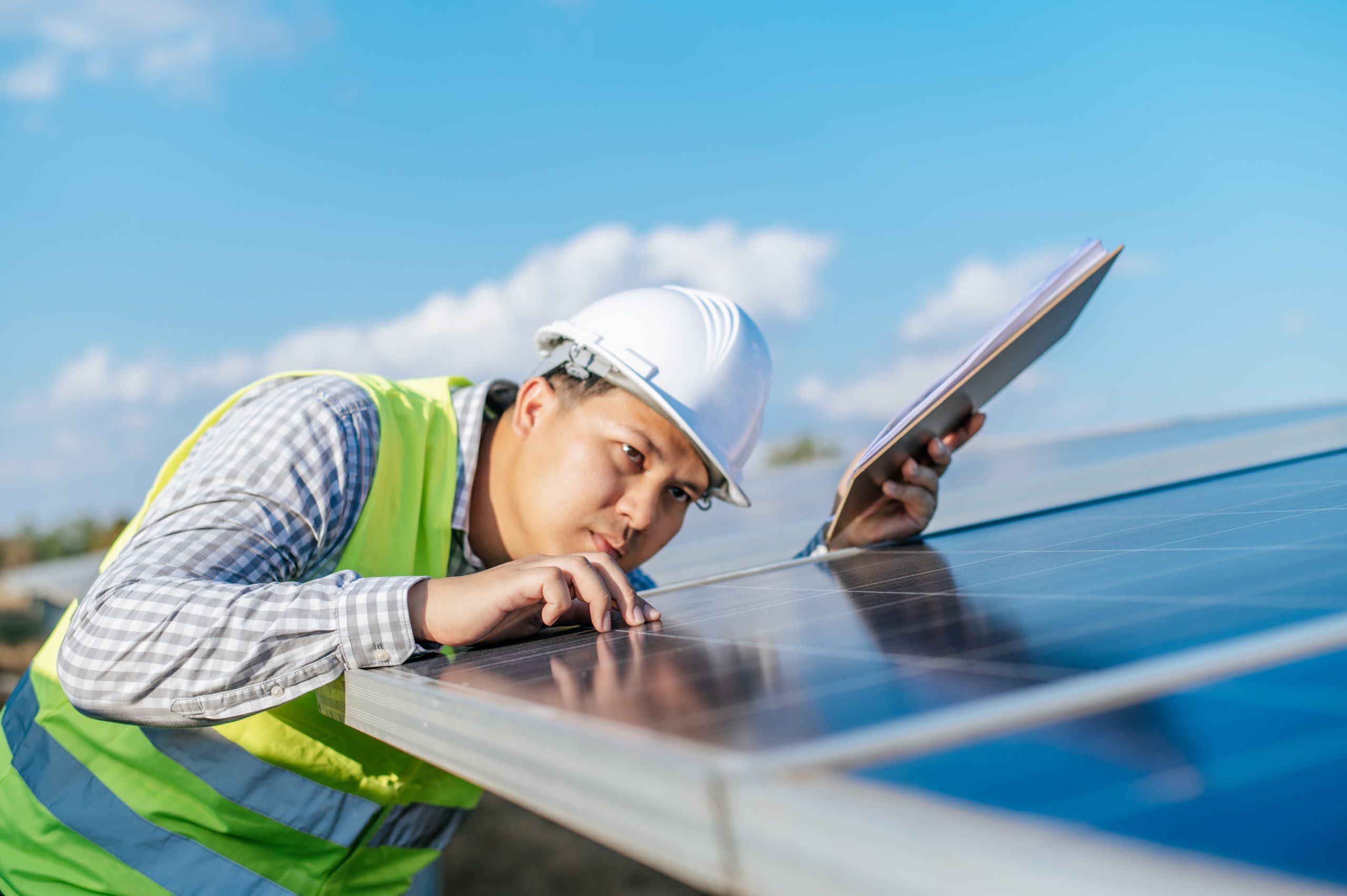 Young Asian technician man checking operation photovoltaic solar Man inspecting solar panels solar panel maintenance in Guildford Surrey Solar Solutions