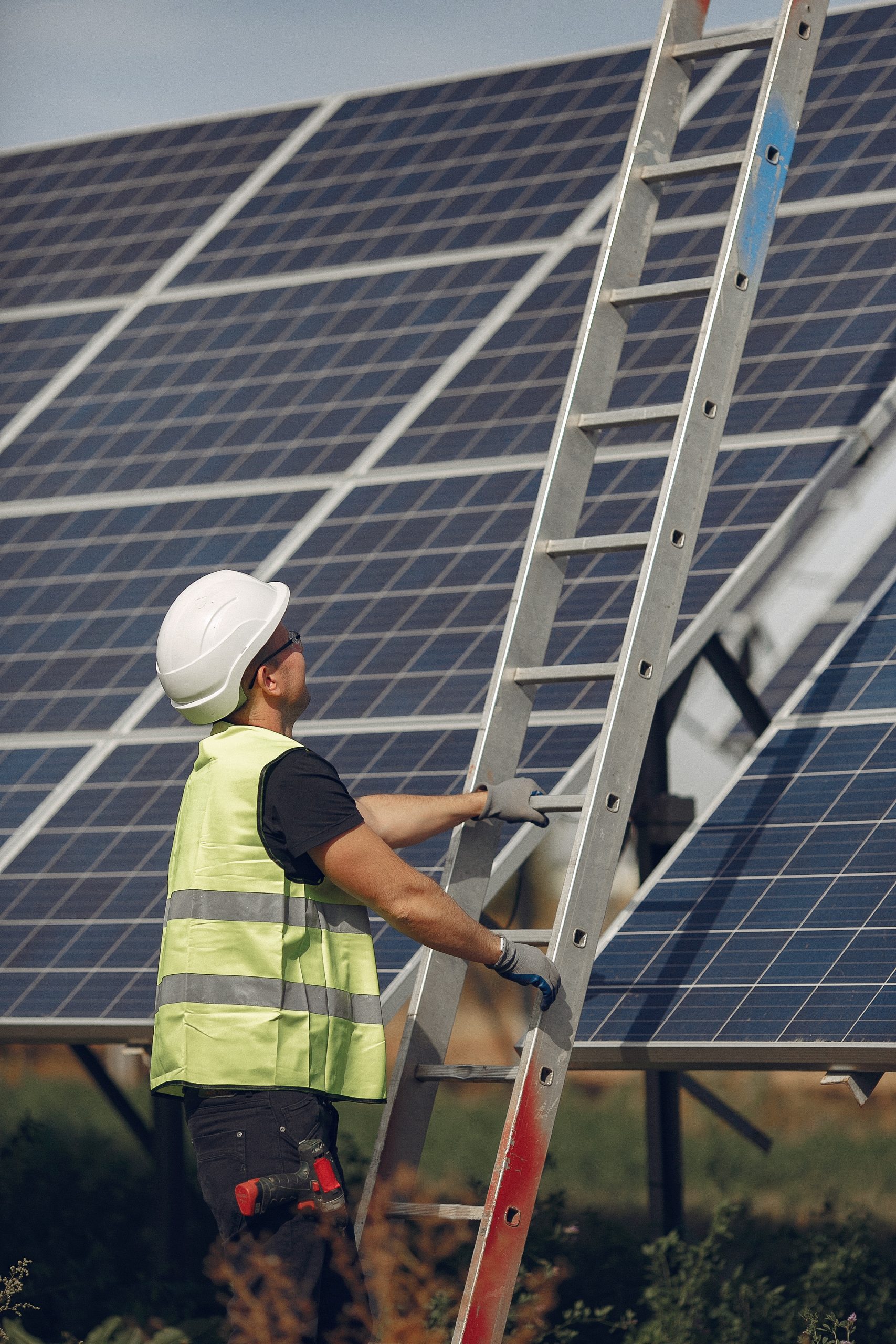 Man in a white helmet near a solar panel Man inspecting and maintaining solar panels solar panel maintenances in Camberley Surrey Solar Solutions
