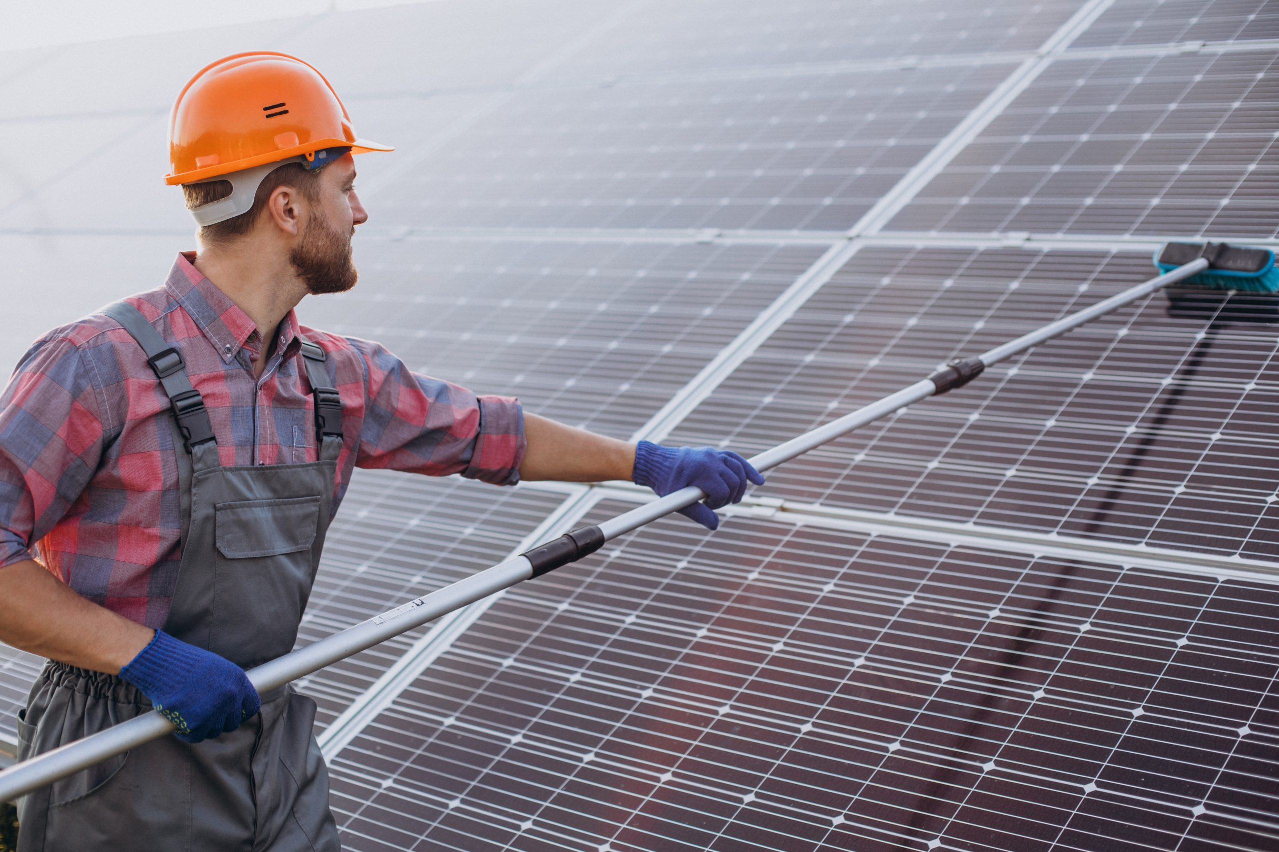 Male worker cleaning solar panels renewable energy electrician solar sustainable energy Renewable Energy Electrician in Camberley Solar panel Installations in Camberley Renewable Energy Electrician in Surrey Solar Solutions Solar Installations in Camberley Surrey